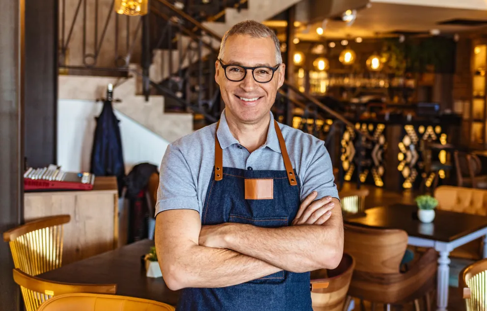 Man in apron crossing his arms and smiling.